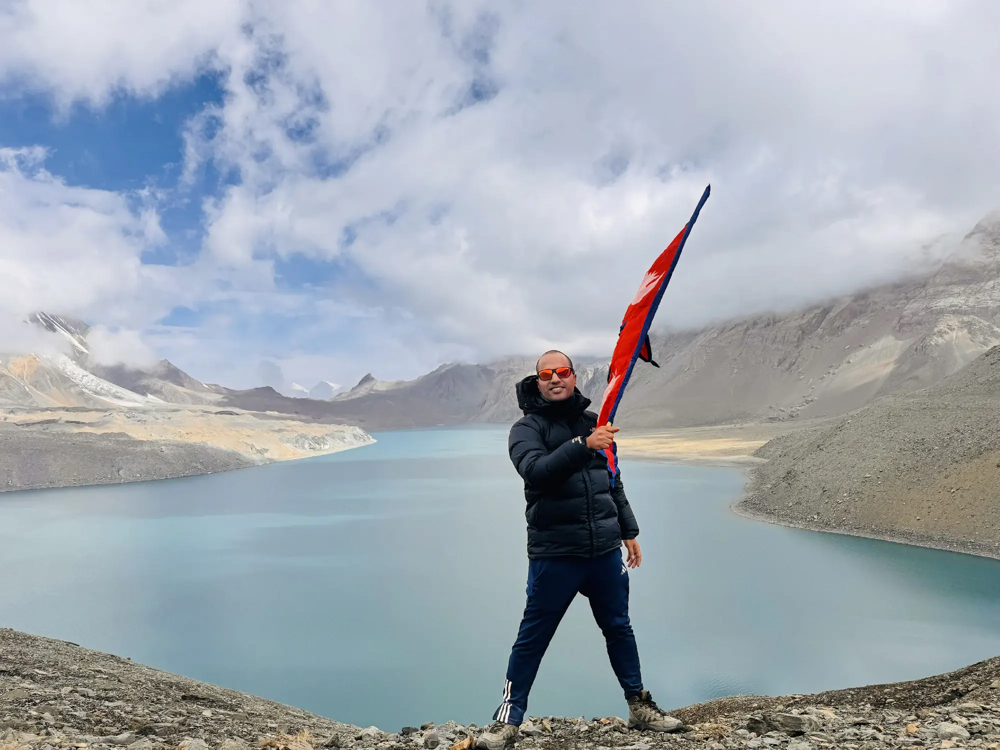 Khagendra Adhikari holding Nepal's flag above Tilicho Lake