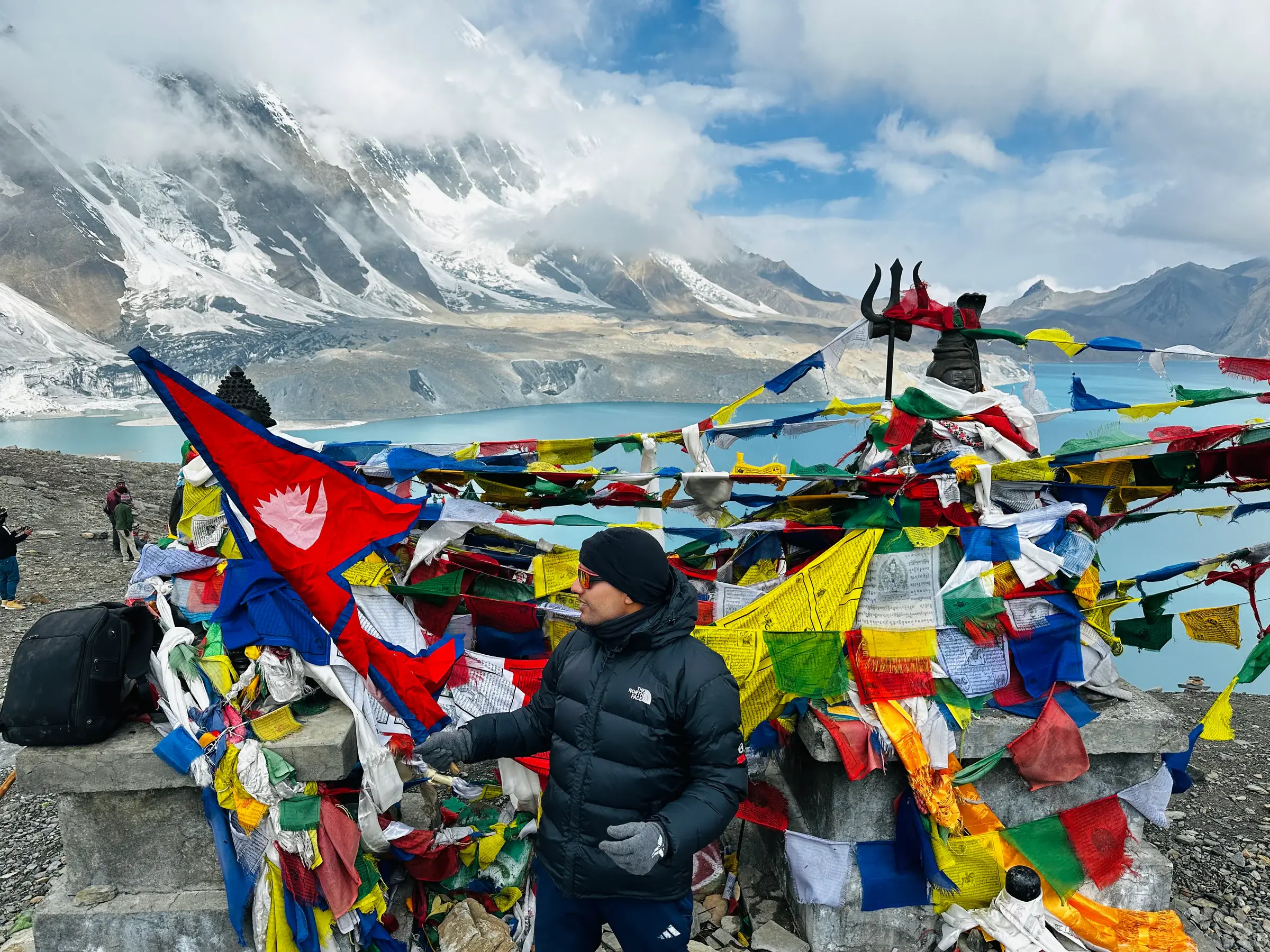 Khagendra among prayer flags above a turquoise Himalayan lake in Nepal